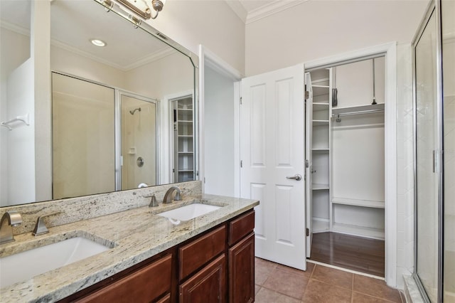 bathroom with crown molding, a sink, a spacious closet, and a shower stall