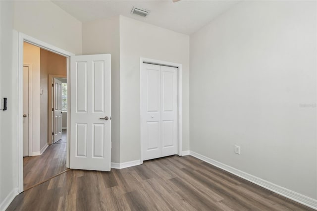 unfurnished bedroom featuring baseboards, visible vents, dark wood finished floors, and a closet