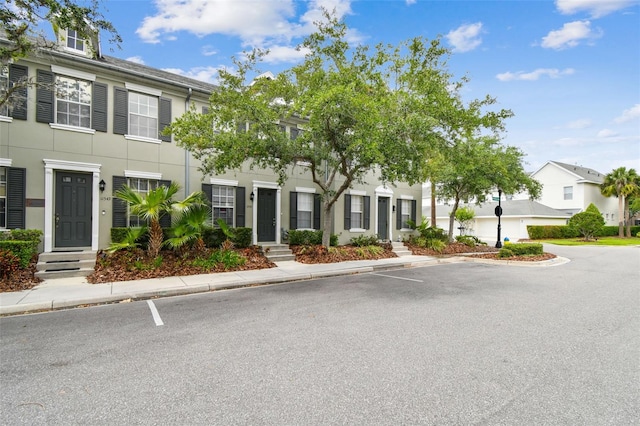 view of front of property featuring a residential view, stucco siding, and uncovered parking