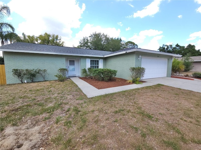 single story home with a garage, a front yard, driveway, and brick siding