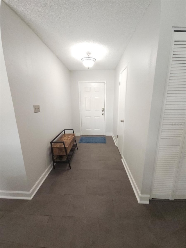hall with a textured ceiling and baseboards