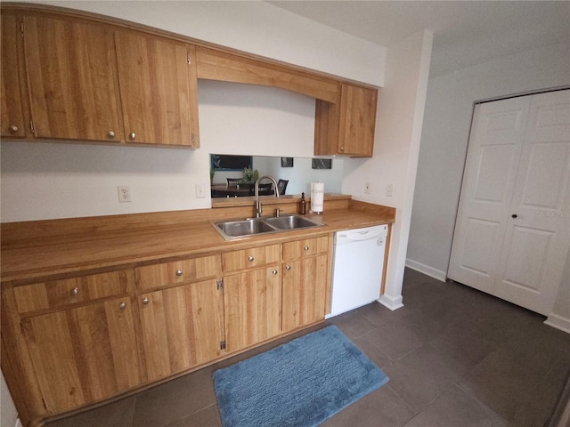 kitchen with dark tile patterned floors, light countertops, brown cabinets, a sink, and dishwasher