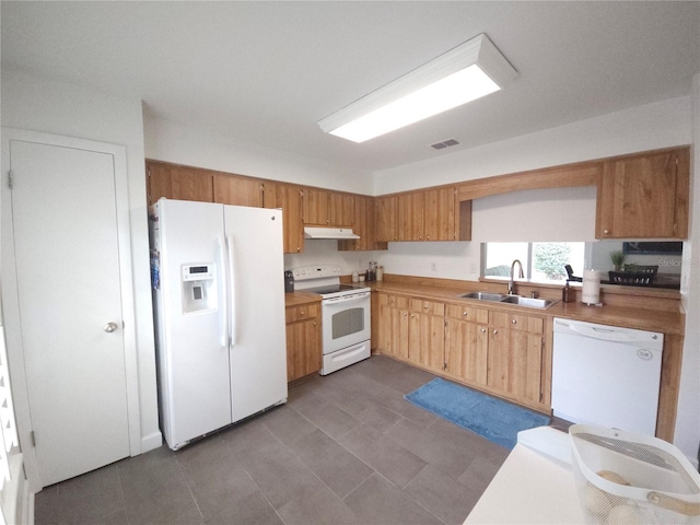 kitchen with visible vents, a sink, dark tile patterned flooring, under cabinet range hood, and white appliances