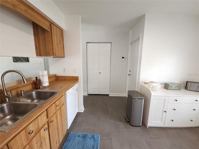 kitchen featuring light countertops, dark tile patterned floors, a sink, and dishwasher
