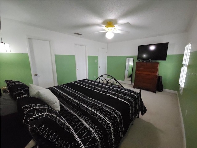 carpeted bedroom with visible vents and a ceiling fan