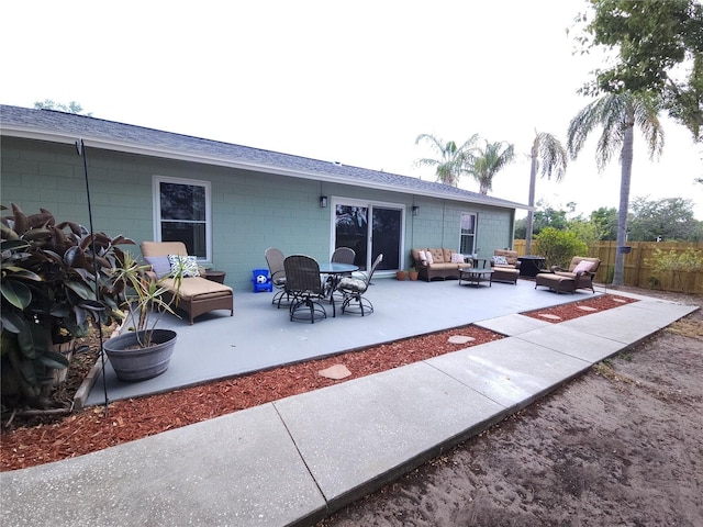 back of house with fence, a patio, concrete block siding, roof with shingles, and an outdoor living space