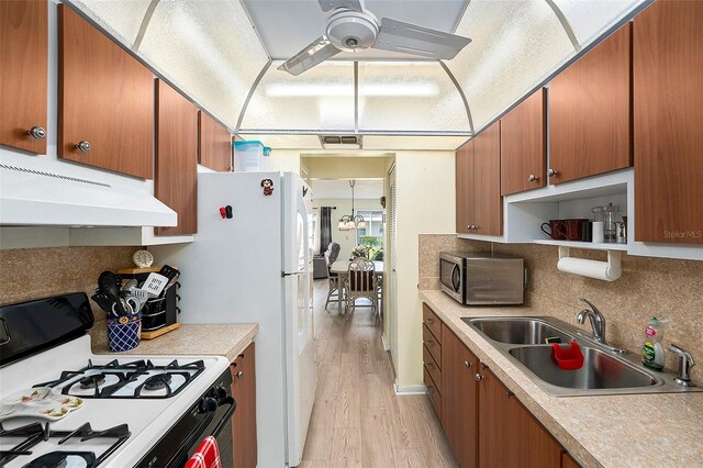 5216 81st St N Unit 2, Saint Petersburg, FL 33709 - kitchen featuring white gas range oven, under cabinet range hood, stainless steel microwave, light wood finished floors, and decorative backsplash