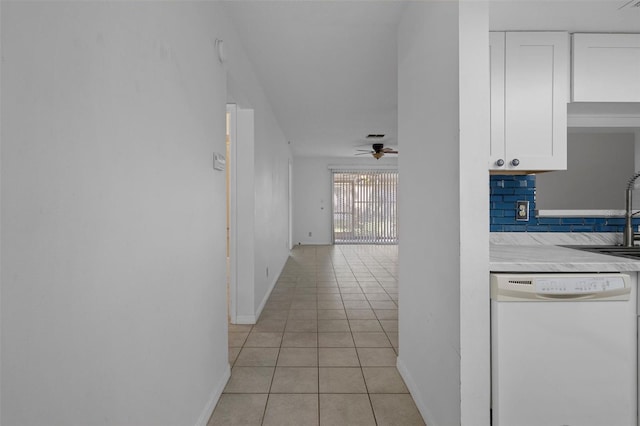 hall featuring baseboards, a sink, and light tile patterned floors