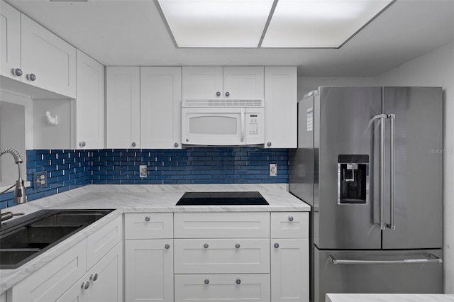 kitchen with backsplash, high quality fridge, a sink, white microwave, and black electric stovetop