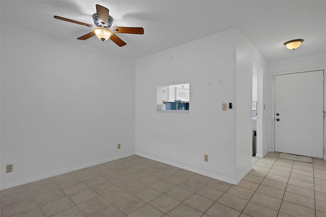 spare room with a textured ceiling, ceiling fan, and baseboards