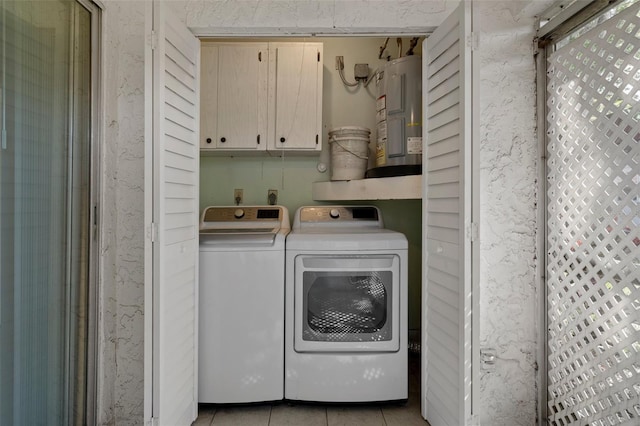 laundry area with cabinet space, water heater, light tile patterned floors, and washer and dryer