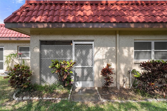 view of side of property with a tile roof and stucco siding