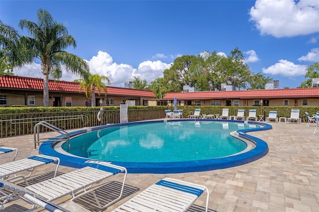 community pool with fence and a patio area