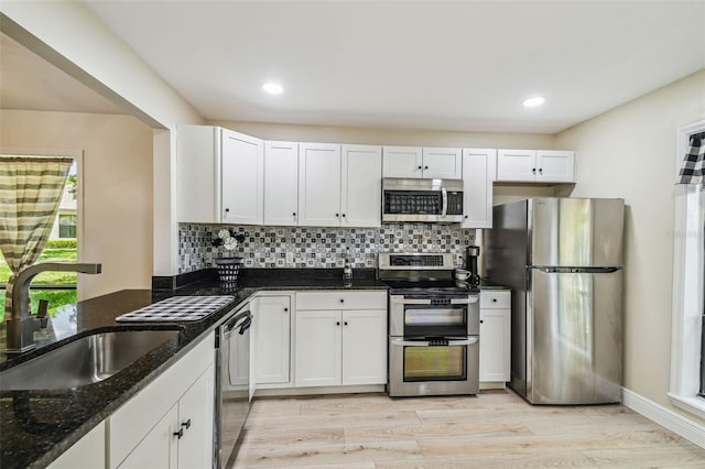 kitchen with light wood-style floors, a sink, decorative backsplash, and stainless steel appliances
