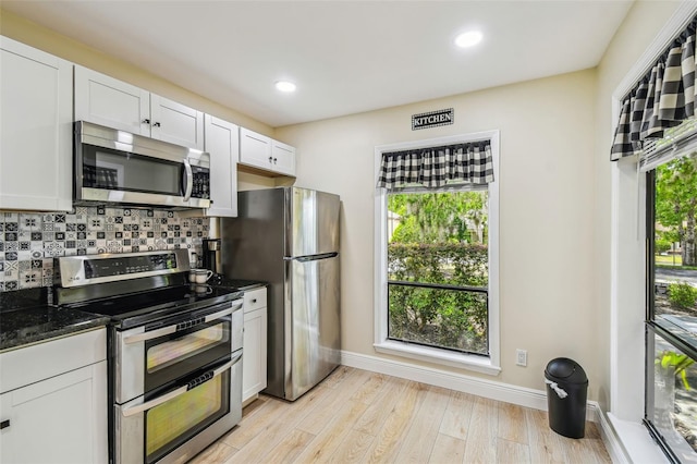 kitchen featuring baseboards, appliances with stainless steel finishes, white cabinets, and tasteful backsplash