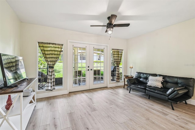 living area with french doors, a ceiling fan, baseboards, and wood finished floors