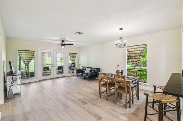 dining area with light wood-style floors, french doors, ceiling fan with notable chandelier, baseboards, and visible vents