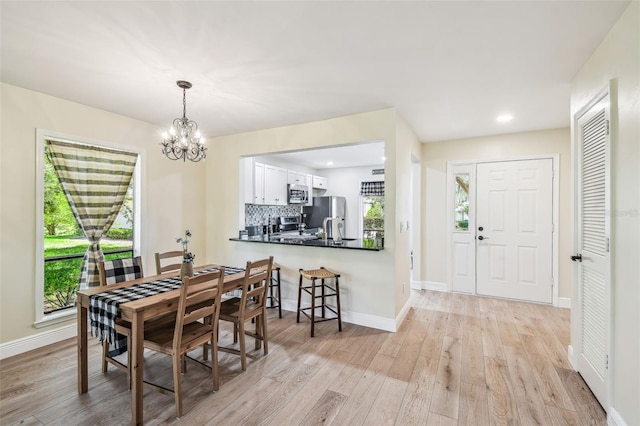 dining area featuring an inviting chandelier, recessed lighting, light wood-style flooring, and baseboards