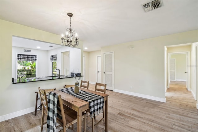 dining room with a notable chandelier, baseboards, visible vents, and light wood-style flooring