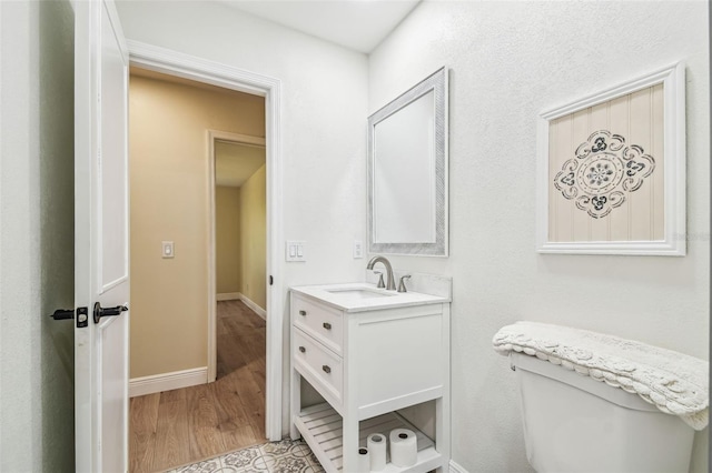 bathroom featuring vanity, baseboards, toilet, and wood finished floors