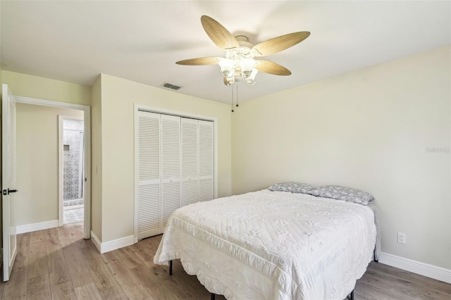 bedroom with visible vents, baseboards, wood finished floors, and a closet