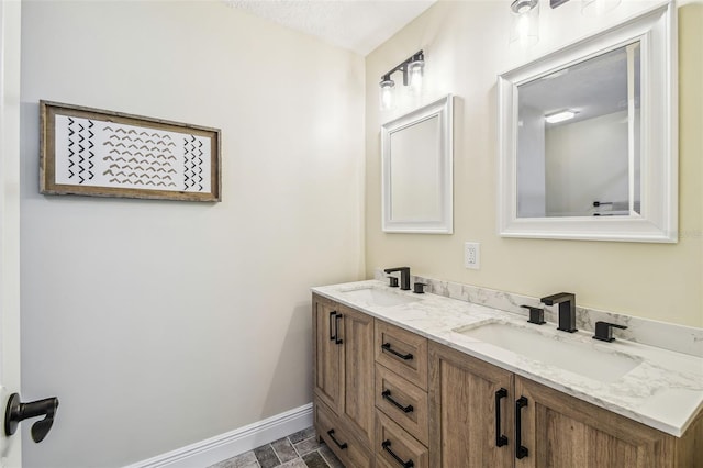 bathroom with a sink, baseboards, and double vanity