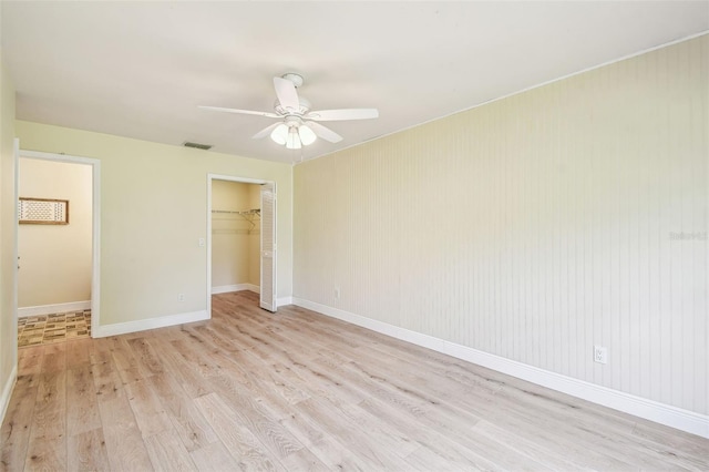 unfurnished bedroom with visible vents, a closet, baseboards, light wood-type flooring, and a spacious closet