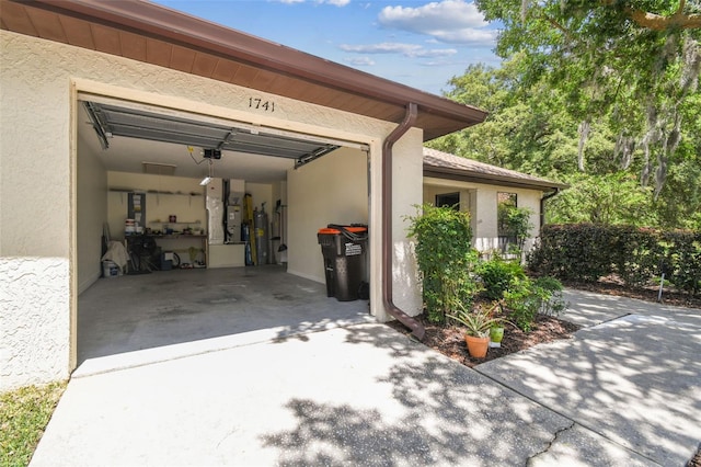 garage with a garage door opener, heating unit, water heater, and concrete driveway