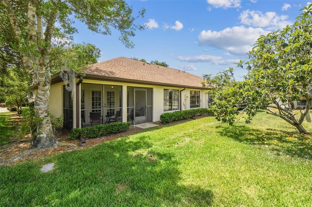 back of property with a lawn, stucco siding, and a sunroom
