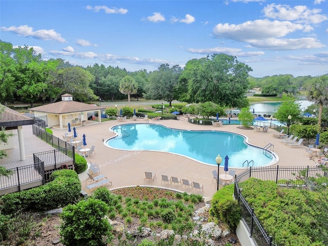 community pool featuring a water view, fence, and a patio area