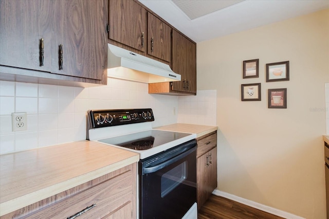 kitchen featuring electric range, under cabinet range hood, light countertops, dark wood-style flooring, and baseboards