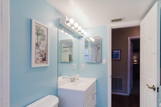 bathroom with visible vents, toilet, and vanity