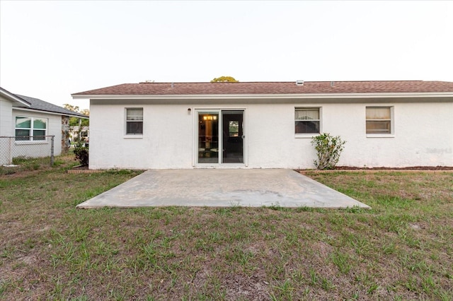 rear view of house featuring a patio, a lawn, stucco siding, and fence