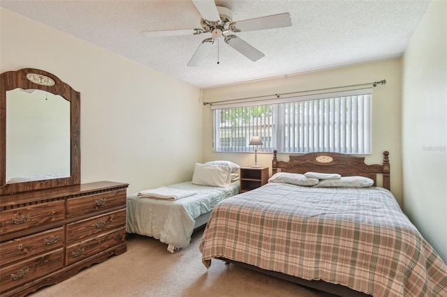 bedroom with ceiling fan, carpet floors, and a textured ceiling