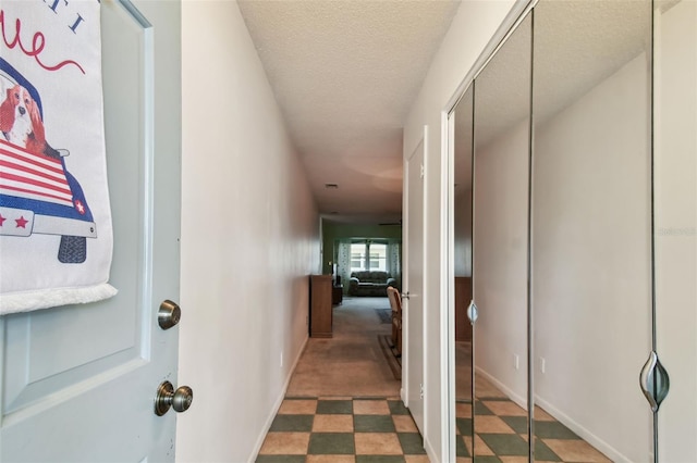 corridor featuring baseboards and a textured ceiling