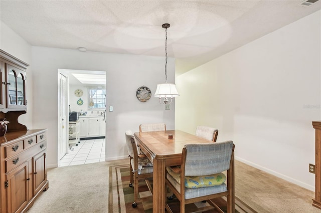 dining space with baseboards and light carpet