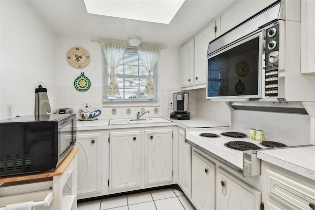 kitchen with white cabinetry, tasteful backsplash, a sink, black microwave, and light countertops