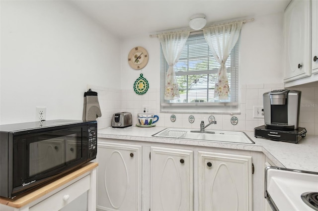 kitchen featuring a sink, decorative backsplash, stove, black microwave, and light countertops