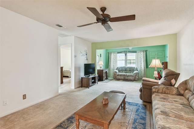 living room featuring a ceiling fan, visible vents, light carpet, and baseboards
