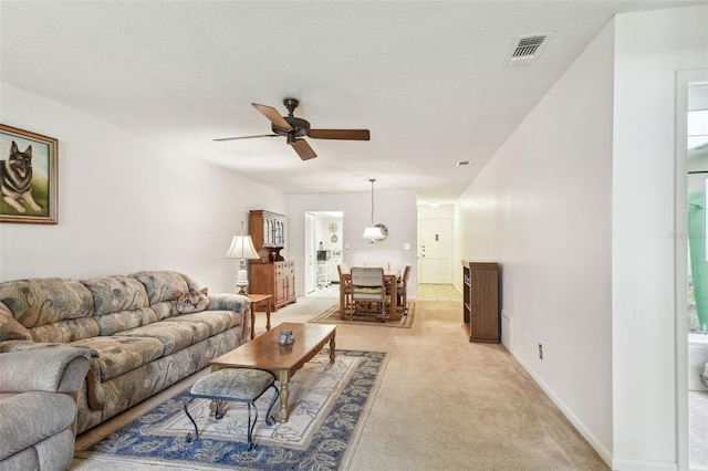 living room with visible vents, ceiling fan, light colored carpet, and baseboards