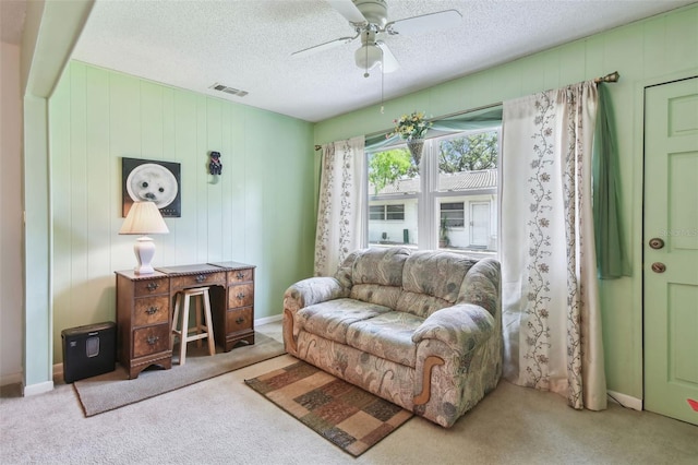 living area with a textured ceiling, visible vents, ceiling fan, and carpet floors