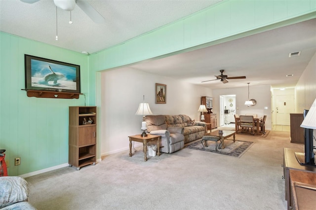 living area with a ceiling fan, visible vents, light carpet, and baseboards