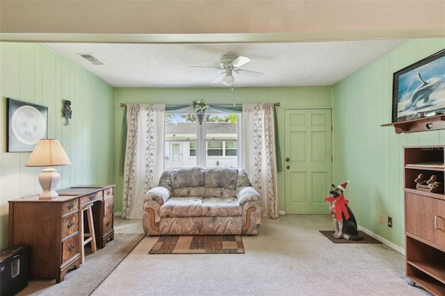 carpeted living room with a textured ceiling, visible vents, a ceiling fan, and baseboards