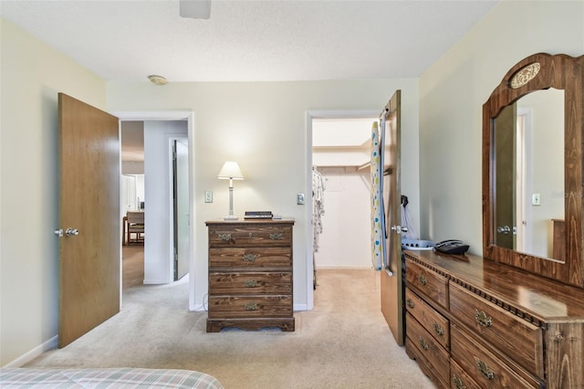 bedroom featuring a spacious closet, baseboards, and light carpet