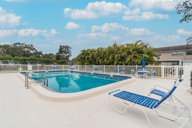 community pool with a patio and fence