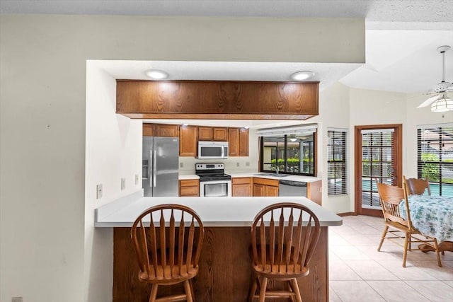 3808 Hollow Wood Dr, Valrico, FL 33594 - kitchen with appliances with stainless steel finishes, a peninsula, light countertops, and a breakfast bar area