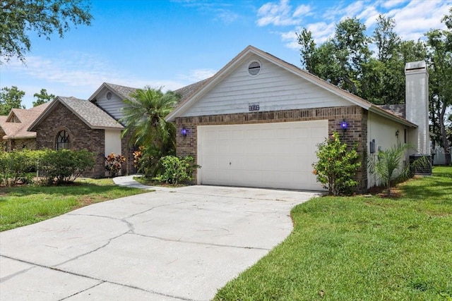 3808 Hollow Wood Dr, Valrico, FL 33594 - ranch-style home featuring driveway, a front yard, a chimney, a garage, and brick siding