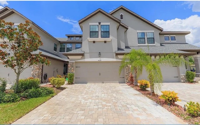 4697 Wandering Way, Wesley Chapel, FL 33544 - view of front of home featuring stucco siding, an attached garage, stone siding, and decorative driveway