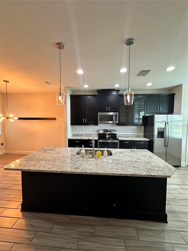 4697 Wandering Way, Wesley Chapel, FL 33544 - kitchen with stainless steel appliances, a sink, decorative backsplash, a center island with sink, and recessed lighting