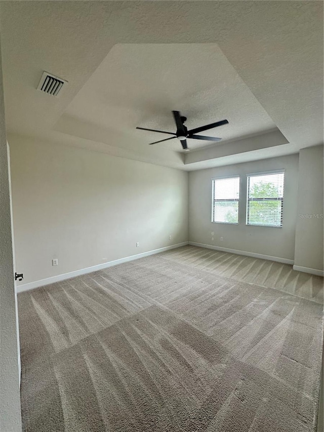 4697 Wandering Way, Wesley Chapel, FL 33544 - empty room with a raised ceiling, a textured ceiling, light carpet, and ceiling fan